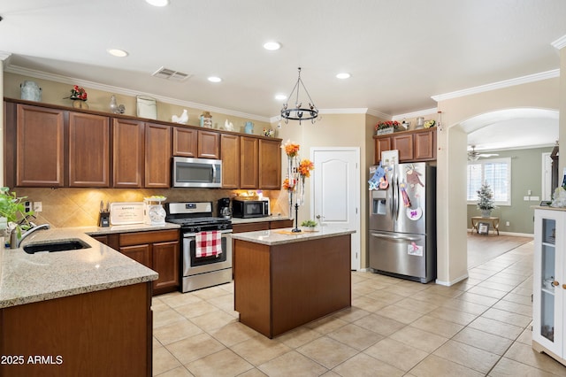 kitchen featuring visible vents, appliances with stainless steel finishes, a center island, light stone countertops, and a sink