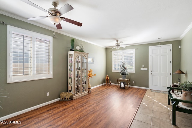 entrance foyer with ornamental molding, wood finished floors, a ceiling fan, and baseboards