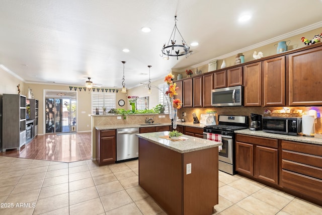 kitchen featuring a center island, light tile patterned floors, hanging light fixtures, appliances with stainless steel finishes, and a peninsula