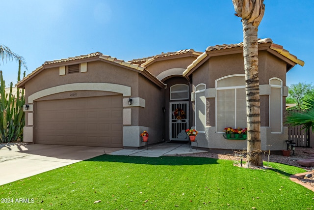 mediterranean / spanish-style home featuring a garage and a front lawn