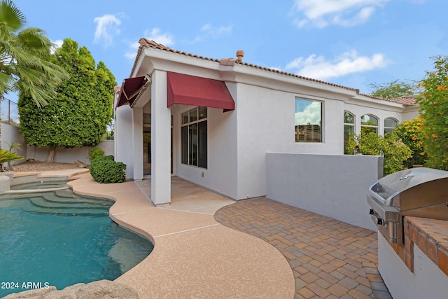 rear view of property with exterior kitchen and a patio