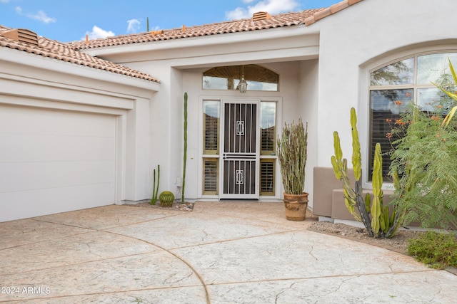 view of exterior entry featuring a garage and a patio area