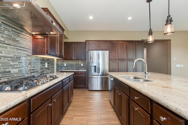 3285 Big Sky Dr, Wickenburg, AZ 85390 - kitchen with stainless steel appliances, a sink, wall chimney exhaust hood, light wood finished floors, and hanging light fixtures