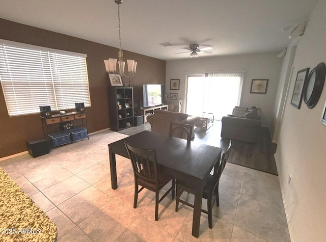 dining space featuring light tile patterned flooring, baseboards, and ceiling fan with notable chandelier