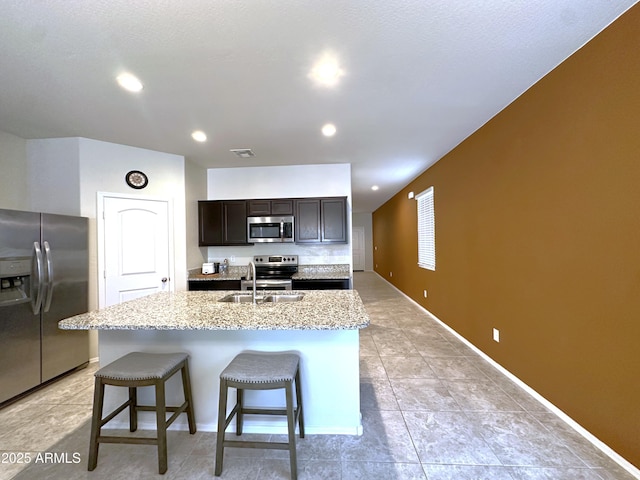 kitchen featuring a sink, a breakfast bar, appliances with stainless steel finishes, a center island with sink, and visible vents