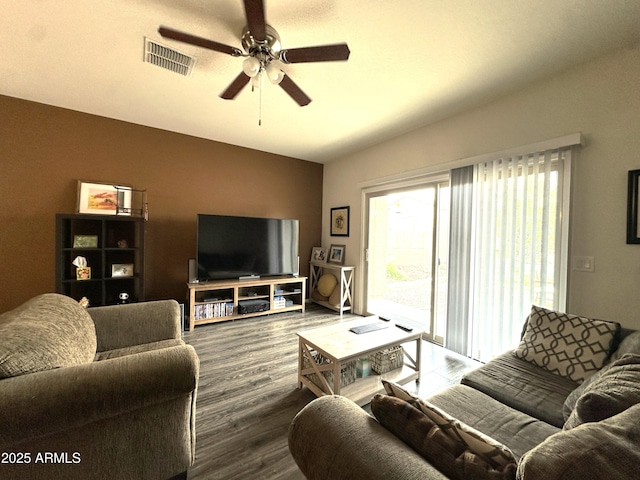 living room featuring vaulted ceiling, dark wood-type flooring, ceiling fan, and visible vents