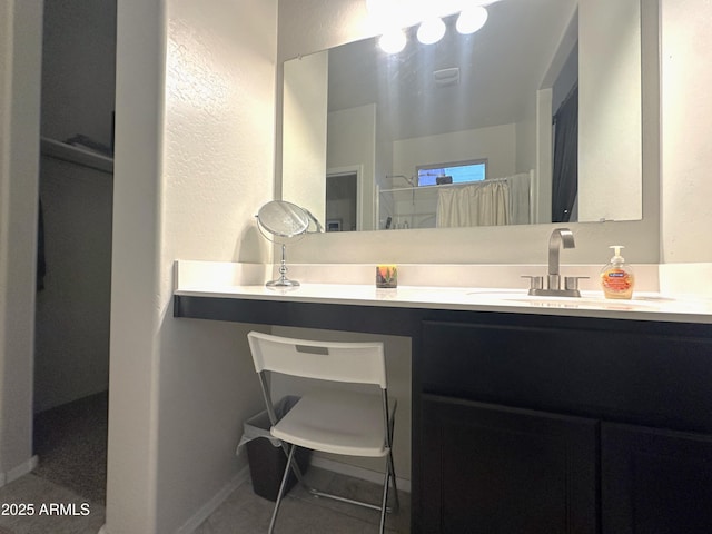 bathroom with a textured wall, a shower, and vanity