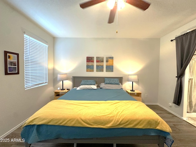 bedroom featuring baseboards, a ceiling fan, and dark wood-style flooring