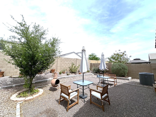 view of patio with a fenced backyard, central air condition unit, and outdoor dining area