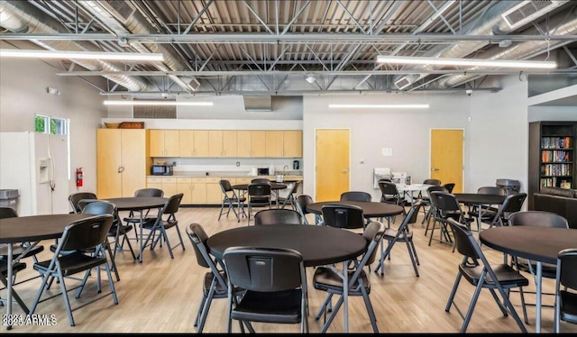 dining space featuring a high ceiling, light wood finished floors, and visible vents