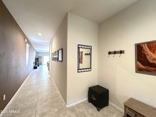 corridor featuring light tile patterned floors and baseboards