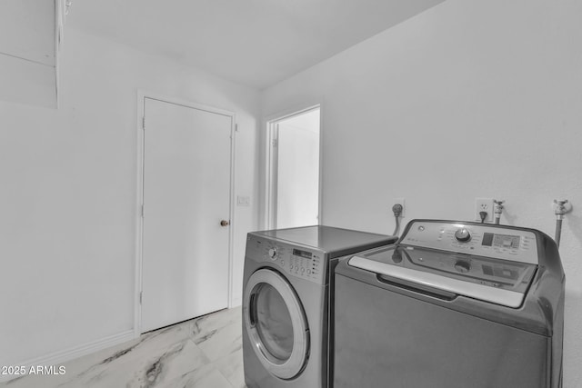 laundry room featuring laundry area, marble finish floor, and washing machine and clothes dryer