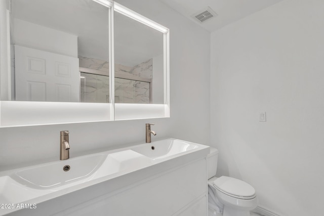 bathroom with a marble finish shower, double vanity, visible vents, toilet, and a sink