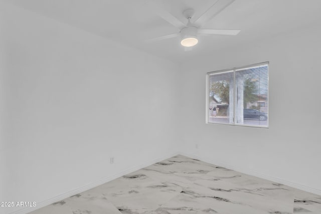 unfurnished room featuring marble finish floor, ceiling fan, and baseboards