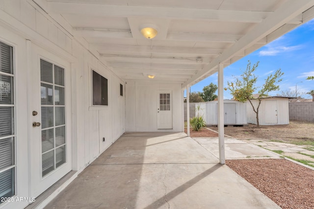 view of patio featuring an outbuilding, fence, and a shed