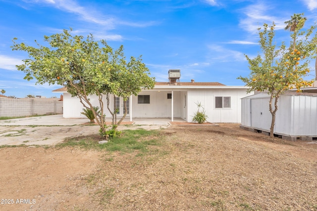 rear view of property featuring a patio area, fence, an outdoor structure, and a storage unit