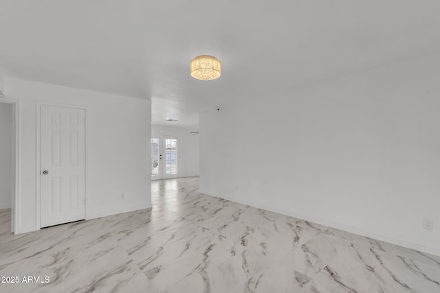 spare room with french doors, marble finish floor, and baseboards