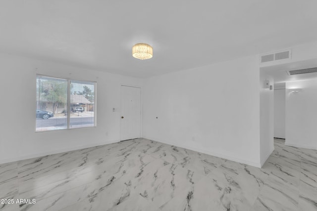 spare room with marble finish floor, baseboards, and visible vents