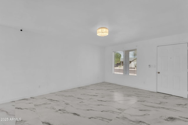 spare room featuring marble finish floor and baseboards