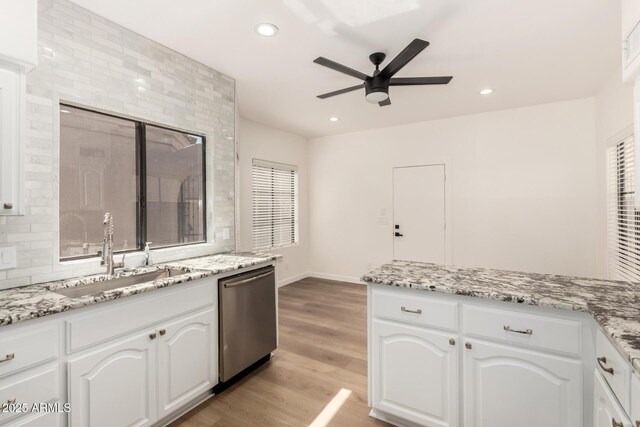 8725 E Via Del Arbor, Scottsdale, AZ 85258 - kitchen with stainless steel dishwasher, ceiling fan, white cabinets, light wood-style flooring, and light stone countertops