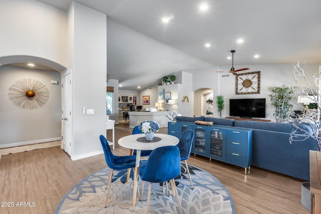 8738 W Runion Dr, Peoria, AZ 85382 - dining room with arched walkways, light wood-style flooring, a ceiling fan, lofted ceiling, and baseboards