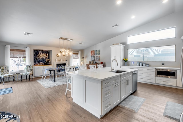 8738 W Runion Dr, Peoria, AZ 85382 - kitchen with a sink, light countertops, a kitchen island with sink, a fireplace, and pendant lighting
