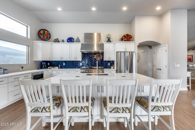 8738 W Runion Dr, Peoria, AZ 85382 - kitchen featuring freestanding refrigerator, island exhaust hood, a large island with sink, arched walkways, and a sink