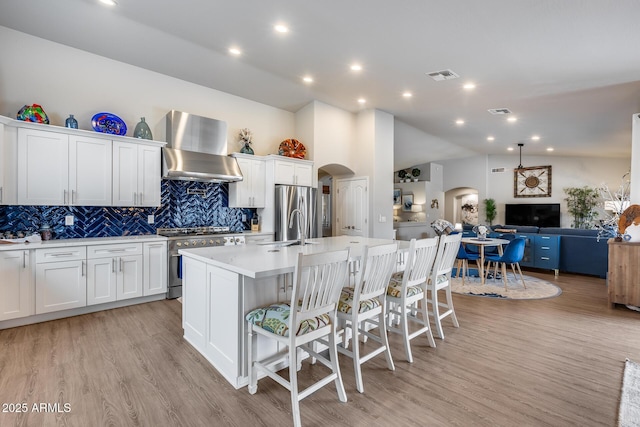 8738 W Runion Dr, Peoria, AZ 85382 - kitchen with arched walkways, appliances with stainless steel finishes, wall chimney range hood, tasteful backsplash, and light countertops