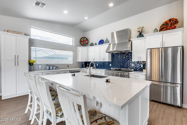 8738 W Runion Dr, Peoria, AZ 85382 - kitchen with stainless steel appliances, wall chimney exhaust hood, a sink, white cabinets, and vaulted ceiling