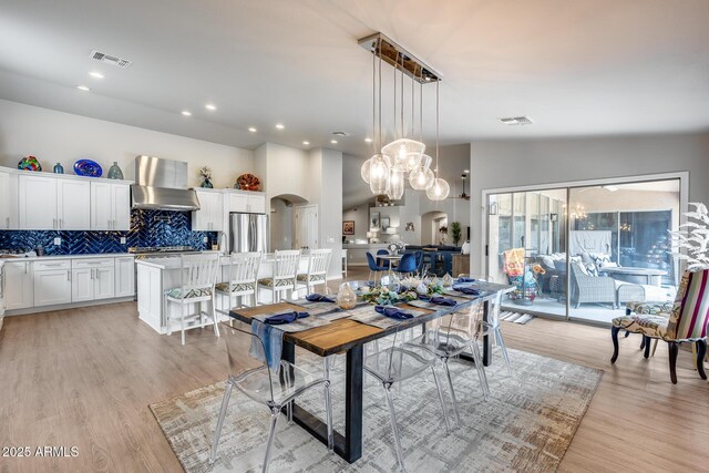 8738 W Runion Dr, Peoria, AZ 85382 - dining space with arched walkways, a chandelier, light wood-type flooring, and vaulted ceiling