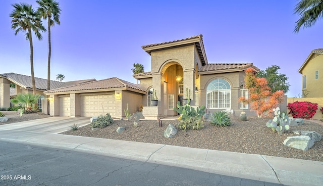 mediterranean / spanish home featuring concrete driveway, a tiled roof, an attached garage, and stucco siding