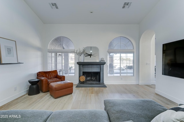 living area with a fireplace, wood finished floors, visible vents, and baseboards