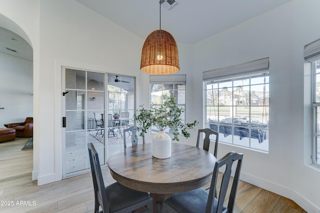 dining room with lofted ceiling, light wood finished floors, visible vents, and baseboards