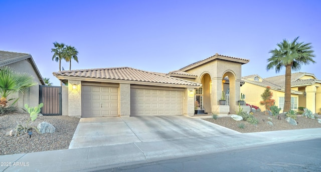 mediterranean / spanish house with concrete driveway, an attached garage, a tiled roof, and stucco siding