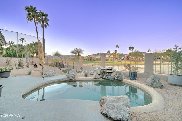 pool at dusk with a residential view, fence, and a fenced in pool