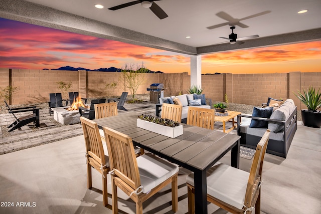 patio terrace at dusk featuring ceiling fan, an outdoor living space with a fire pit, and a grill