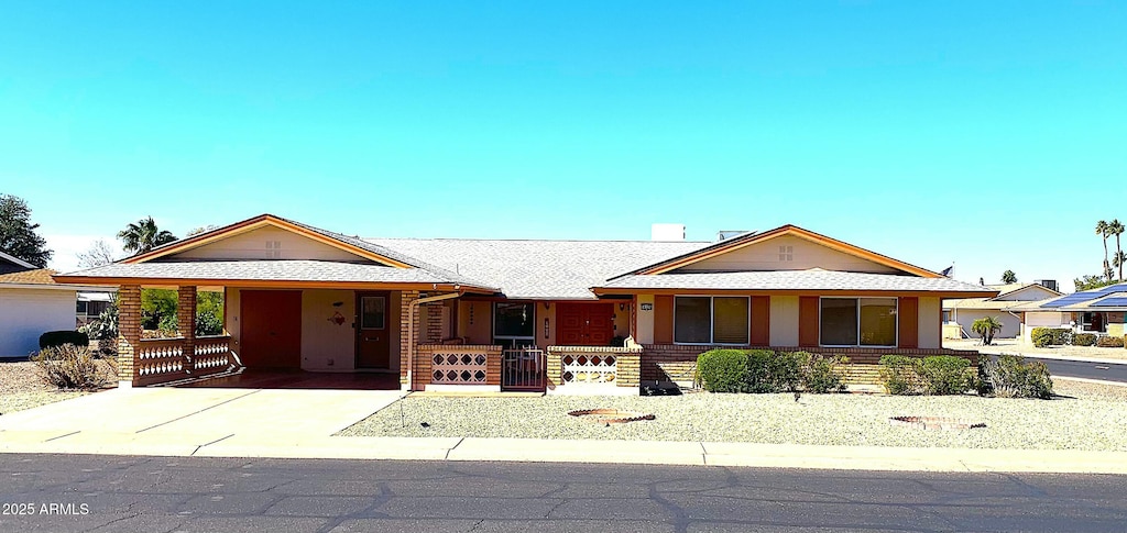 single story home with stucco siding, a carport, roof with shingles, and concrete driveway