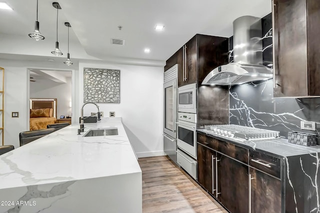 kitchen with sink, backsplash, pendant lighting, white appliances, and exhaust hood