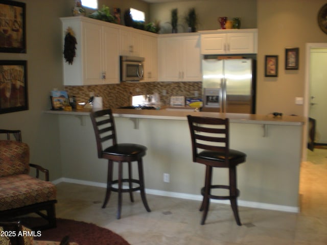 32764 N 68th Pl, Scottsdale, AZ 85266 - kitchen with backsplash, appliances with stainless steel finishes, a kitchen breakfast bar, and a peninsula