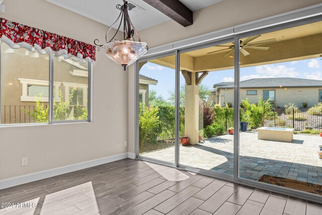 doorway featuring beamed ceiling, ceiling fan with notable chandelier, and hardwood / wood-style floors