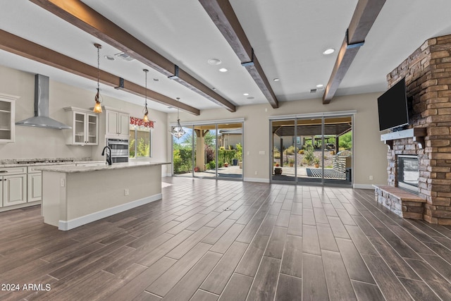 unfurnished living room with beamed ceiling, dark hardwood / wood-style flooring, and a stone fireplace