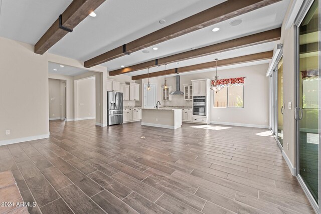 unfurnished living room with beamed ceiling, sink, and hardwood / wood-style floors