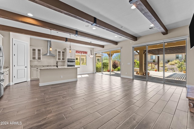 unfurnished living room with beamed ceiling and hardwood / wood-style floors