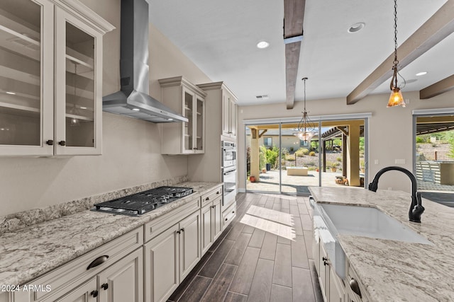 kitchen with beamed ceiling, dark hardwood / wood-style flooring, pendant lighting, wall chimney range hood, and appliances with stainless steel finishes