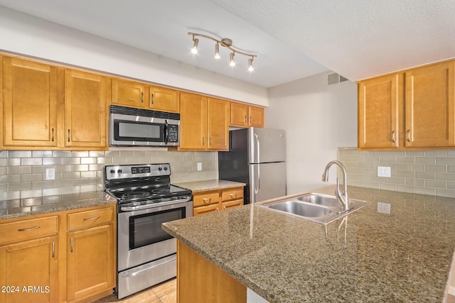 kitchen featuring appliances with stainless steel finishes, decorative backsplash, sink, and track lighting