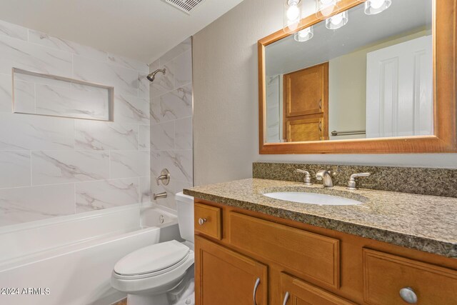 full bathroom featuring vanity, tiled shower / bath, and toilet