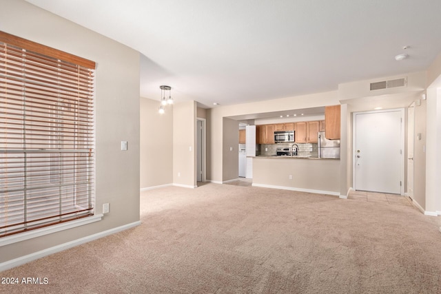 unfurnished living room with sink and light carpet