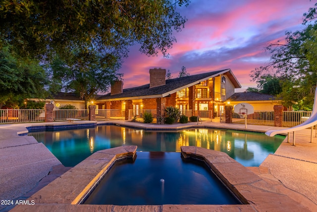 pool at dusk with a water slide and a patio area