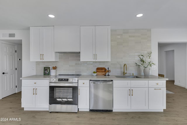 kitchen featuring sink, light hardwood / wood-style flooring, decorative backsplash, appliances with stainless steel finishes, and white cabinetry