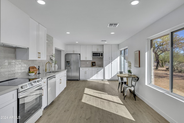 kitchen with light hardwood / wood-style floors, white cabinetry, sink, and appliances with stainless steel finishes